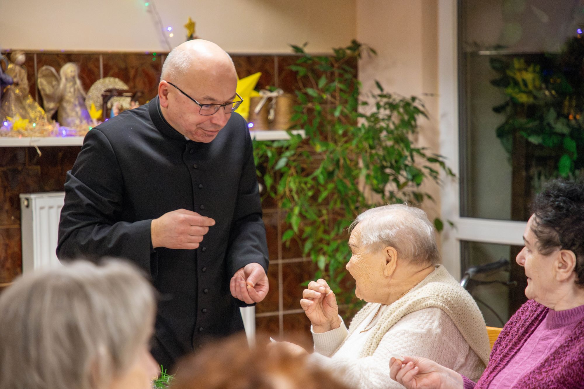 Ksiądz dzieli się opłatkiem z seniorką